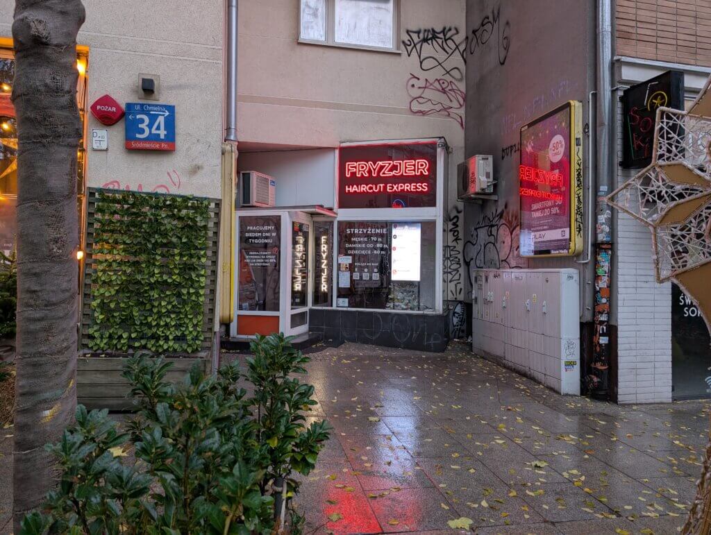 Wejście do salonu fryzjerskiego Haircut Express przy ul. Chmielnej 34 w Warszawie – neon „Fryzjer Haircut Express”